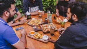 a group of people sitting around a table with pizzas and drinks