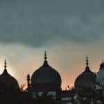 the sun is setting behind the domes of a building