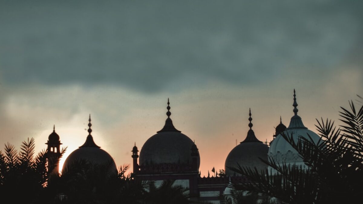 the sun is setting behind the domes of a building