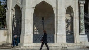 person in suit jacket walking on front of black gate