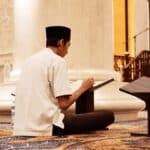 a man sitting on the floor reading a book
