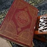 The quran sits open on a wooden book stand.