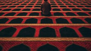 man in red shirt kneeling on red and black carpeted floor